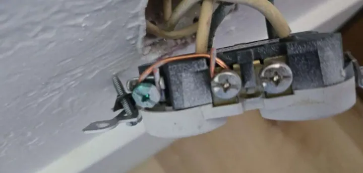Outlet with a copper jumper wire connecting the neutral and ground terminals, a classic bootleg ground