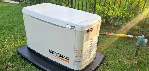 Generac whole-home standby generator on a pad with its gas connection beside a backyard fence