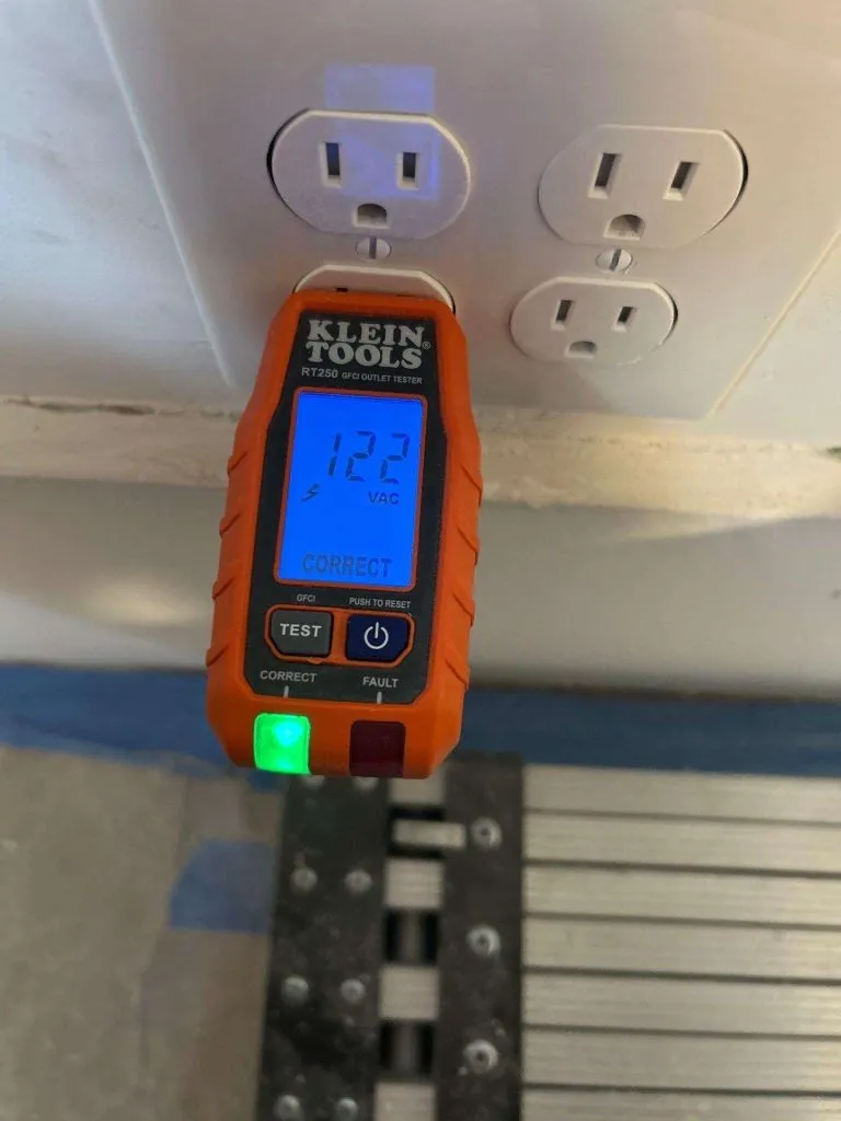 Electrician testing a receptacle during a home electrical safety inspection